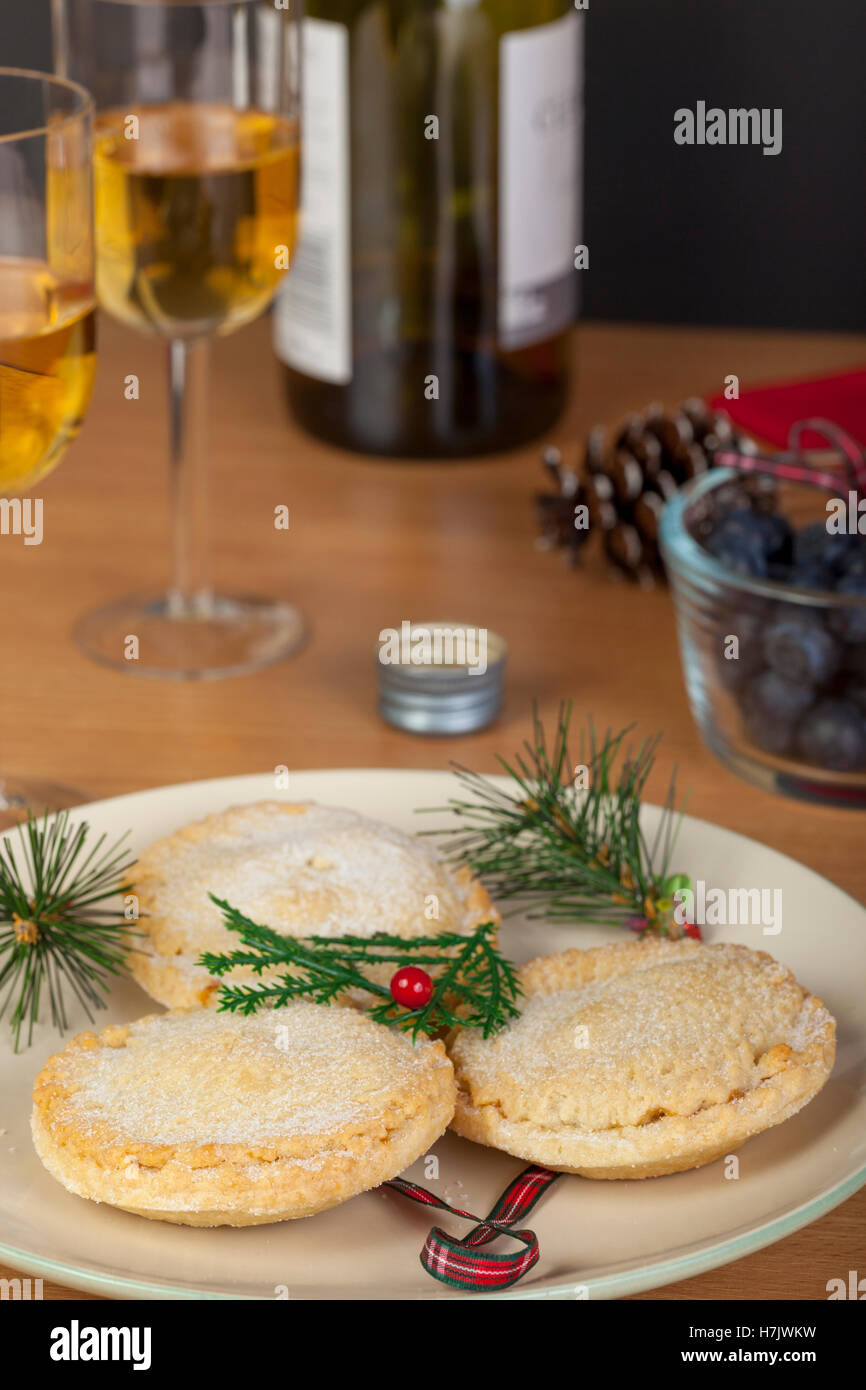 Plaqué frais petits pâtés sur une table avec 2 verres de vin à Noël Banque D'Images