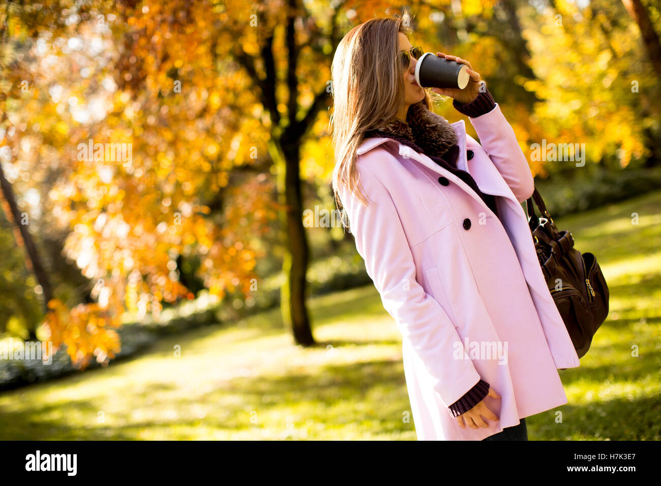 Jeune femme avec du café pour aller dans le parc en automne Banque D'Images