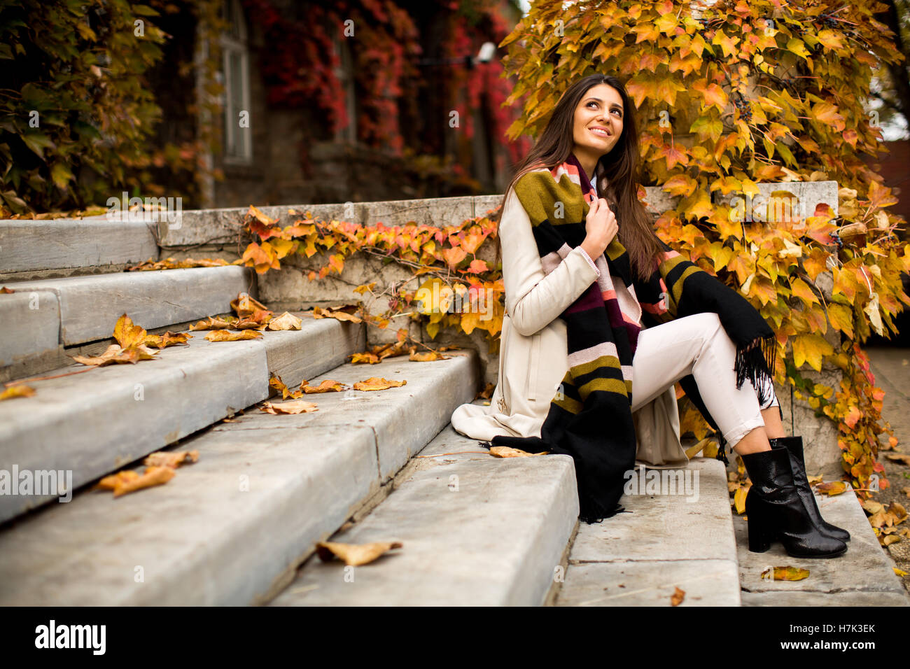 Jeune femme assise sur les marches à l'extérieur à l'automne 24 Banque D'Images