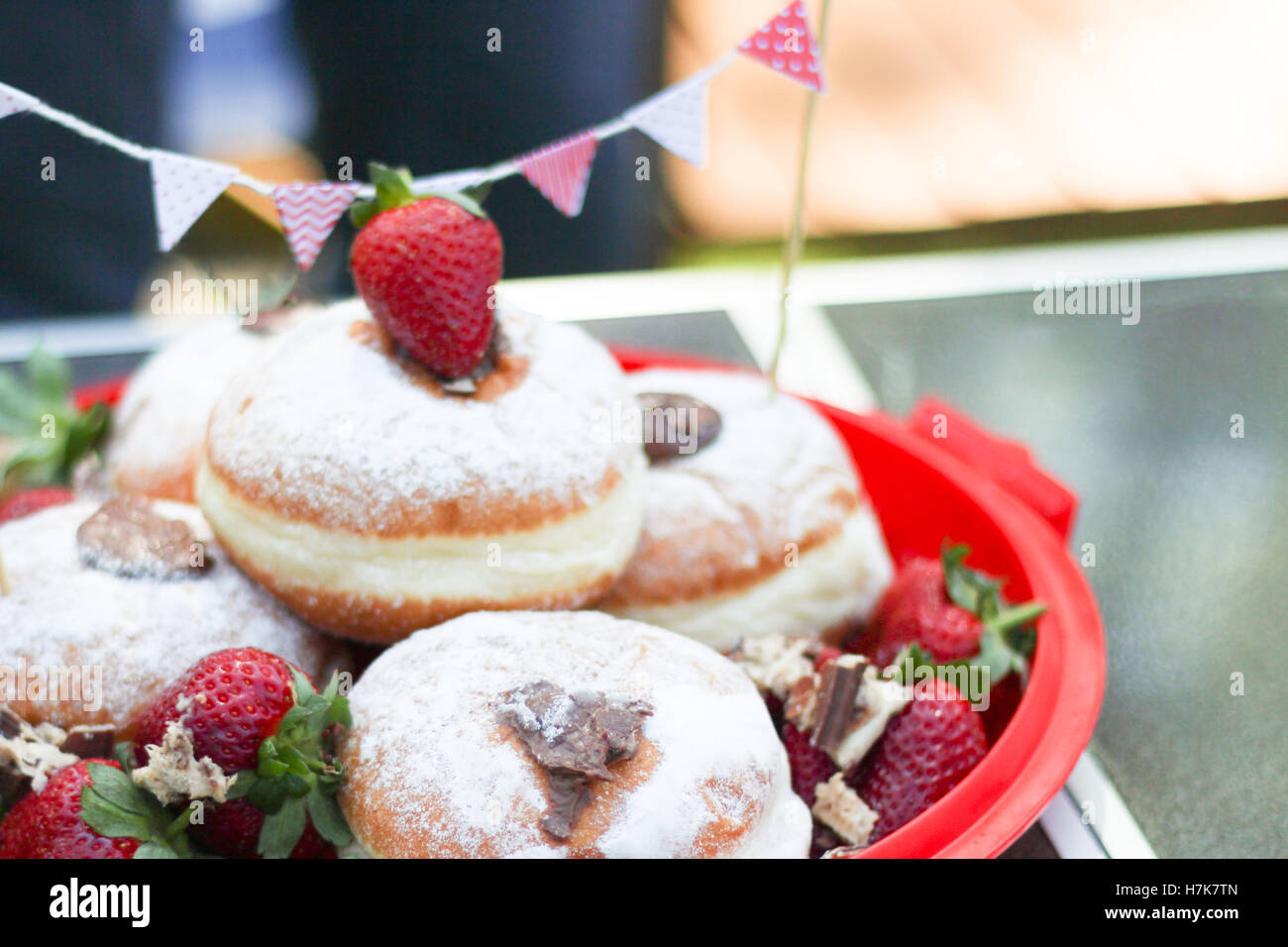 Strawberry tops un tas de Chocolat noir fourré donuts - pique-nique en plein air avec bunting Banque D'Images