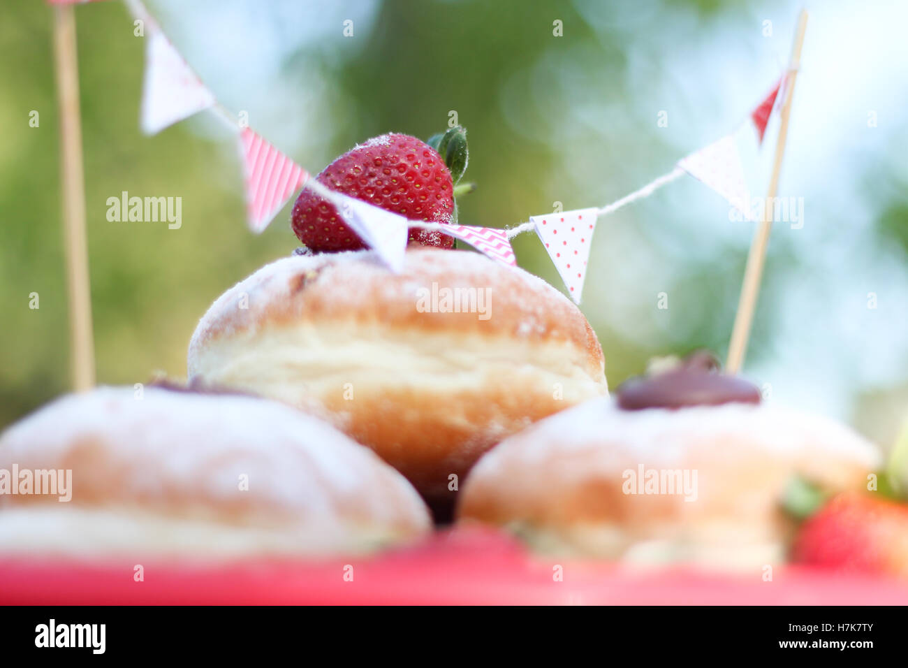 Strawberry tops un tas de Chocolat noir fourré donuts - pique-nique en plein air avec bunting Banque D'Images