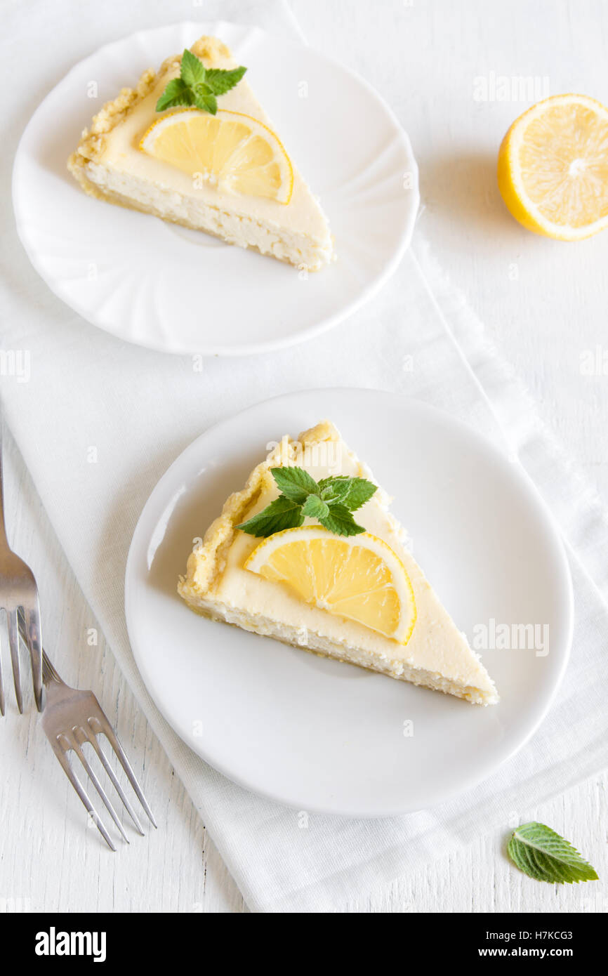 De délicieux morceaux de gâteau au fromage au citron fait maison avec des tranches de citron et menthe sur fond blanc avec copie espace Banque D'Images