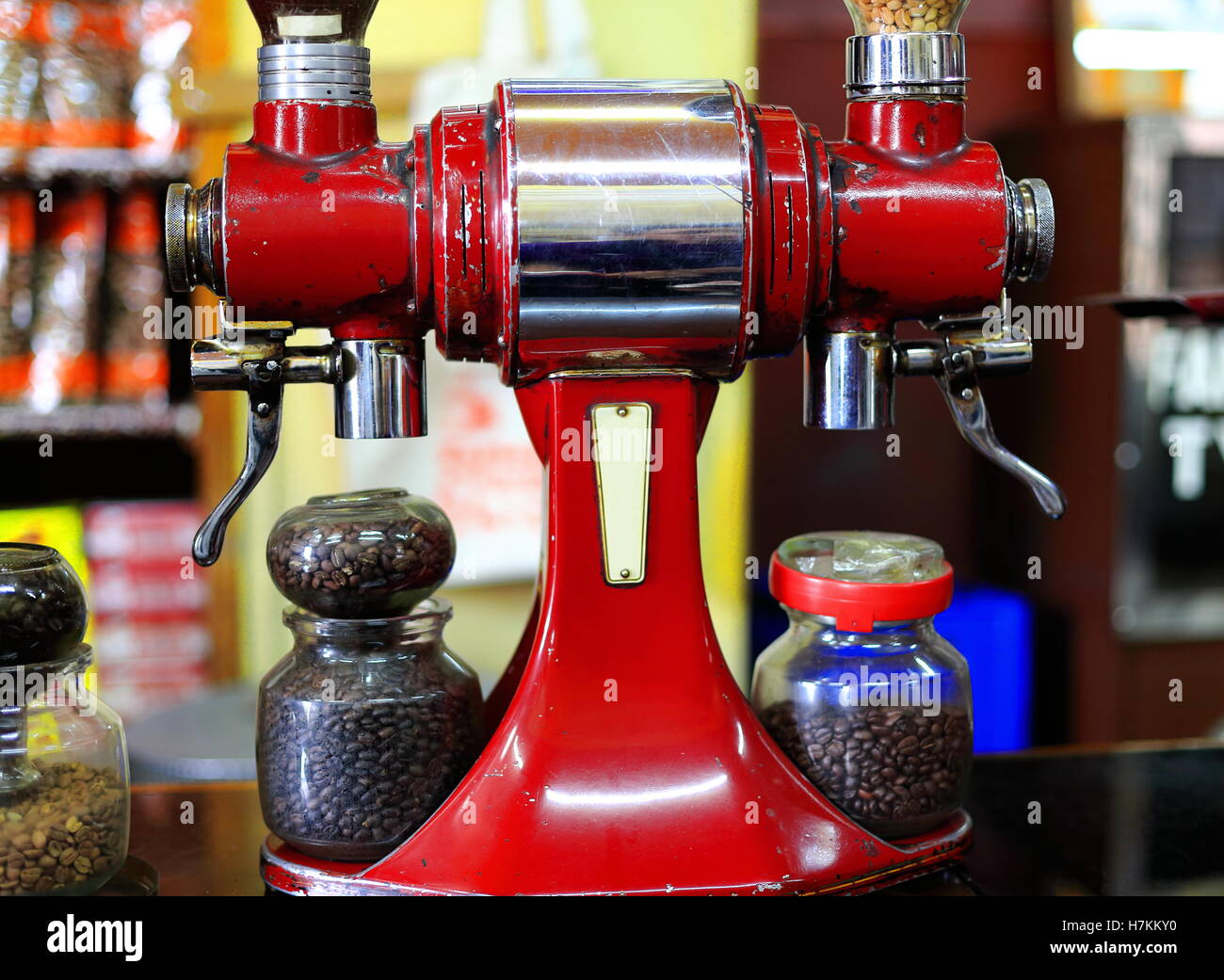 Ancien peint rouge vintage style italien rectifieuse de café ainsi que des pots de verre contenant des grains de café torréfiés prêts à être la masse. Banque D'Images