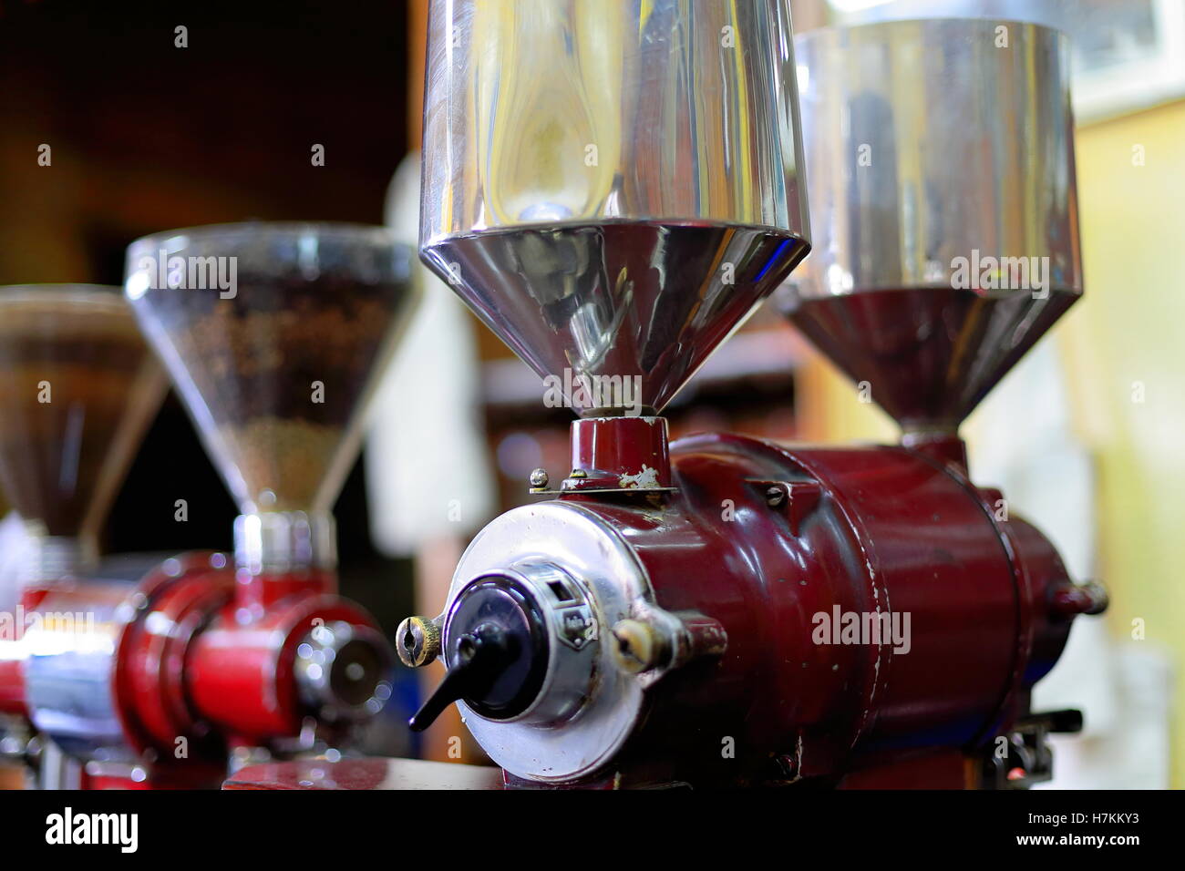 Ancien peint rouge vintage style italien moulins à café avec pots en métal contenant des grains de café torréfiés prêts à être la masse. Banque D'Images