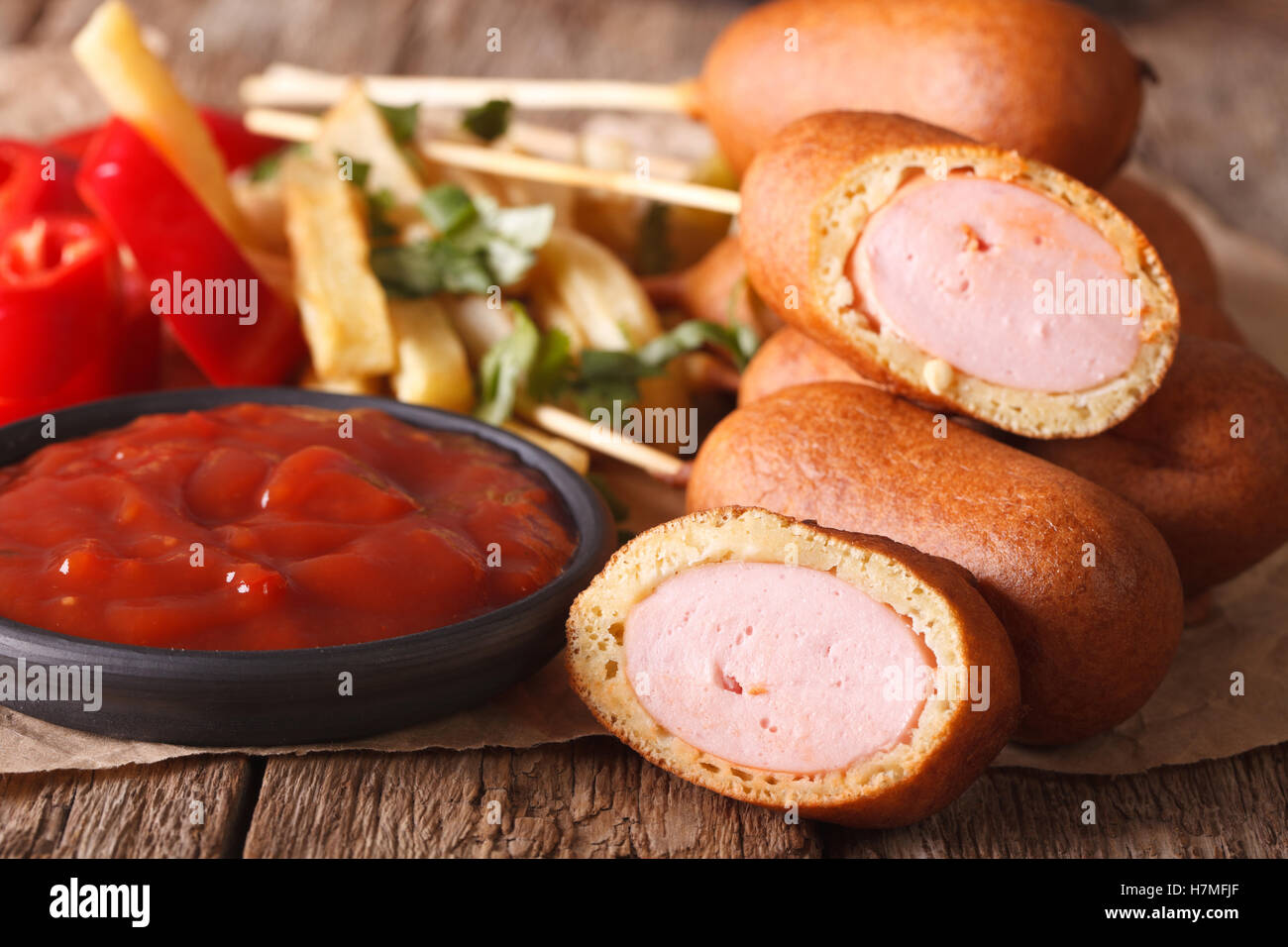 Les chiens de maïs avec du ketchup macro sur la table horizontale et rustique. Banque D'Images