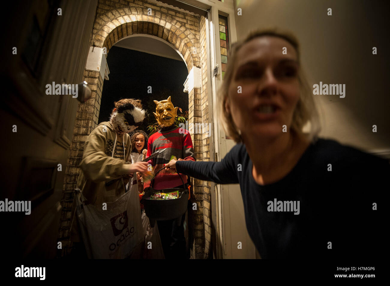 Une femme répond à la porte à l'Halloween Trick or Treaters Banque D'Images