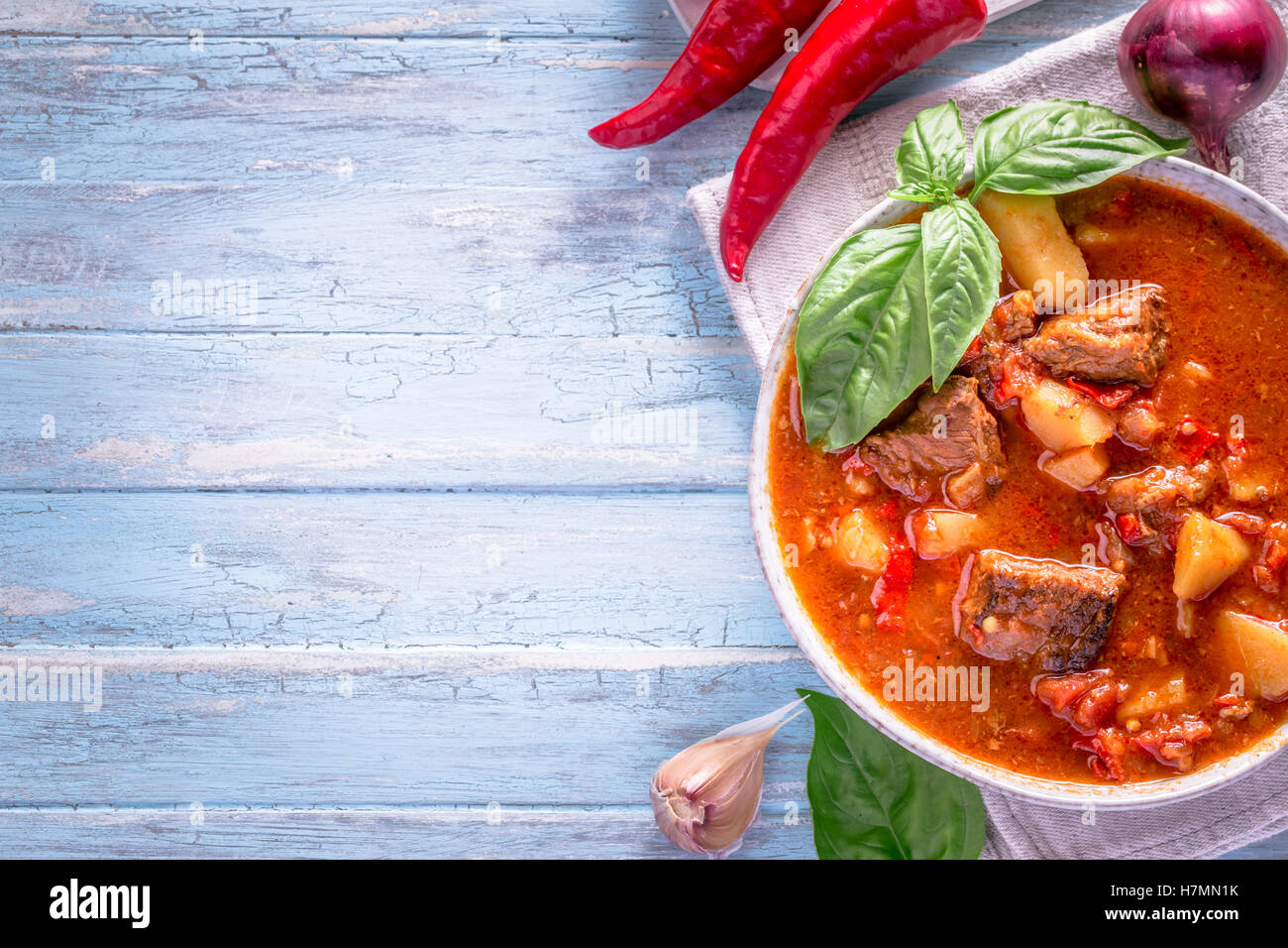 Bol de goulash sur fond cyan clair avec l'exemplaire de l'espace. Repas traditionnel hongrois - ragoût de boeuf. Banque D'Images