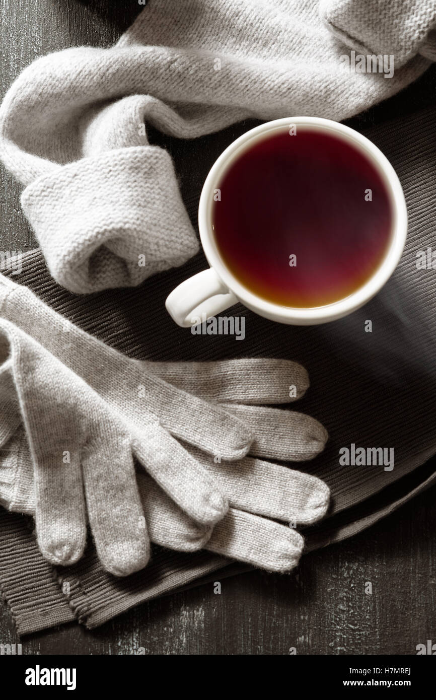 Tasse à café et tricoté à la main les choses sur un fond noir. Des vêtements d'hiver. Concept atmosphère confortable avec une tasse de café dans la wi Banque D'Images
