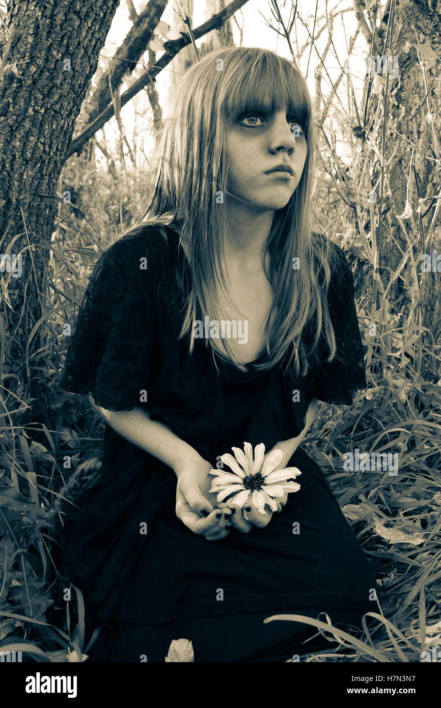 Zombie fantomatique girl alone in woods holding white flower en noir et blanc Banque D'Images