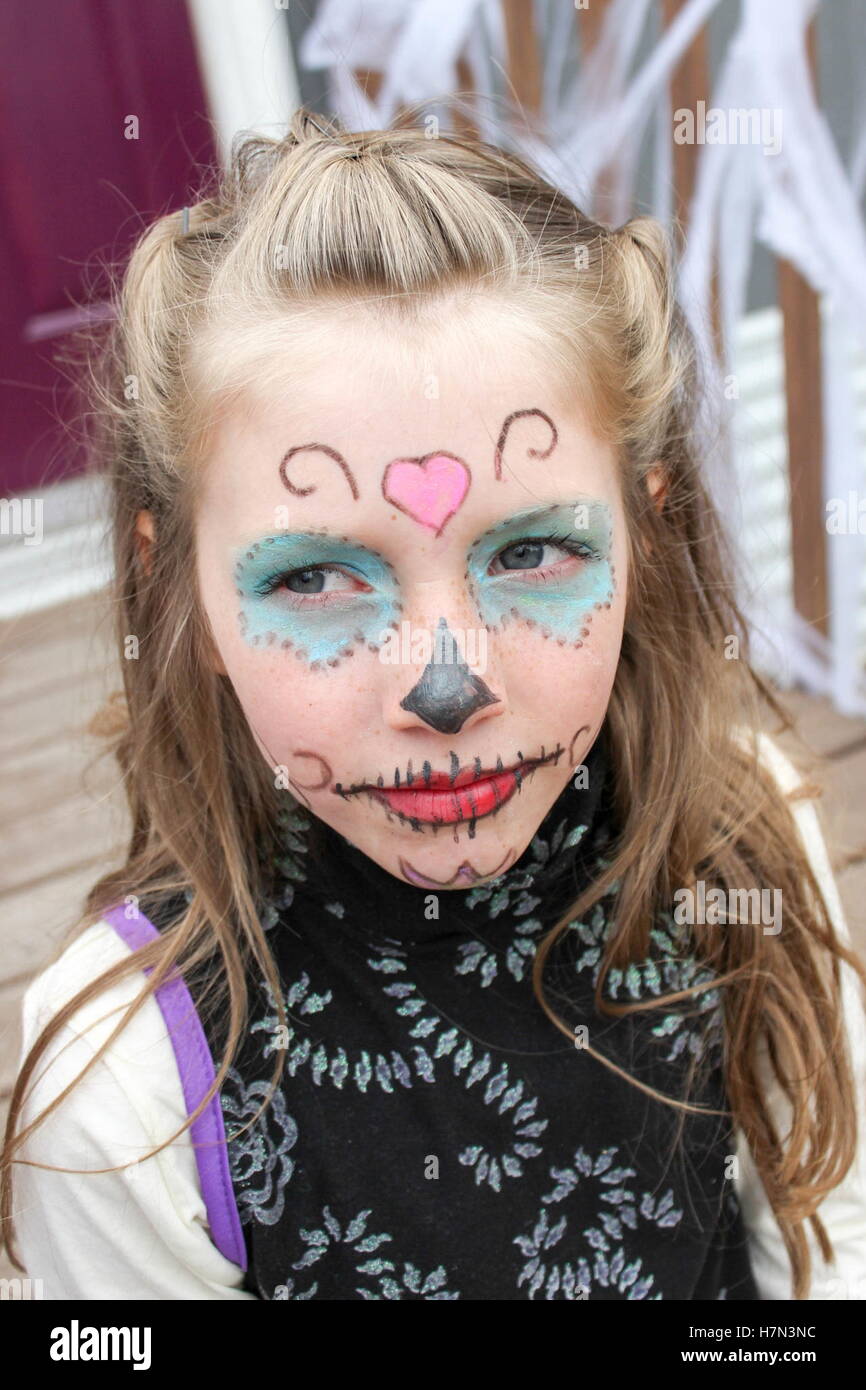 Jeune fille avec crâne en sucre maquillage halloween peint sur son visage assis sur les marches de bois Banque D'Images