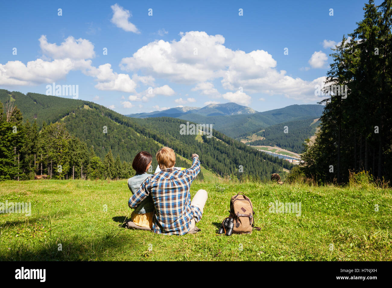 Voyageant couple sitting on the prairie alpine et regardant la carte Banque D'Images