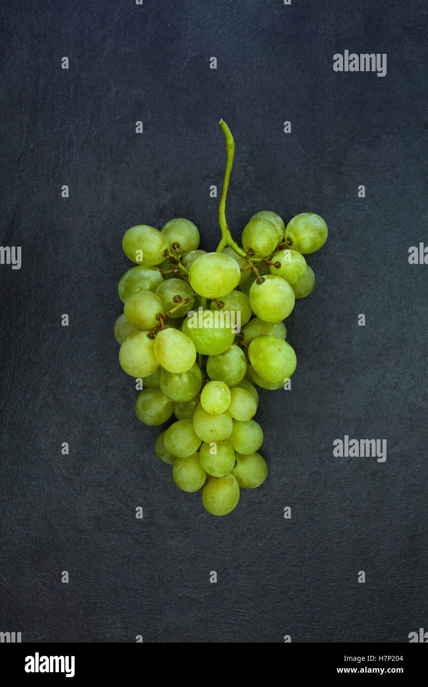 Des tas de raisin vert isolé sur fond noir en ardoise gris foncé Banque D'Images