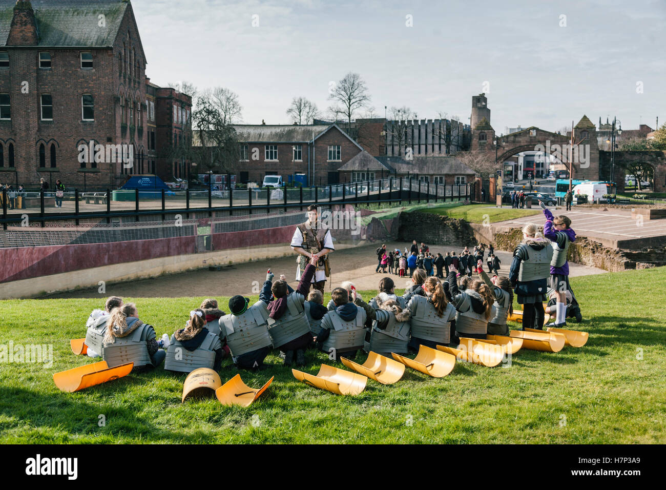 Chester, Royaume-Uni. 26 janvier, 2016. Les enfants de l'école s'asseoir à l'amphithéâtre romain de Chester, les mains levées pour répondre à une question. Banque D'Images