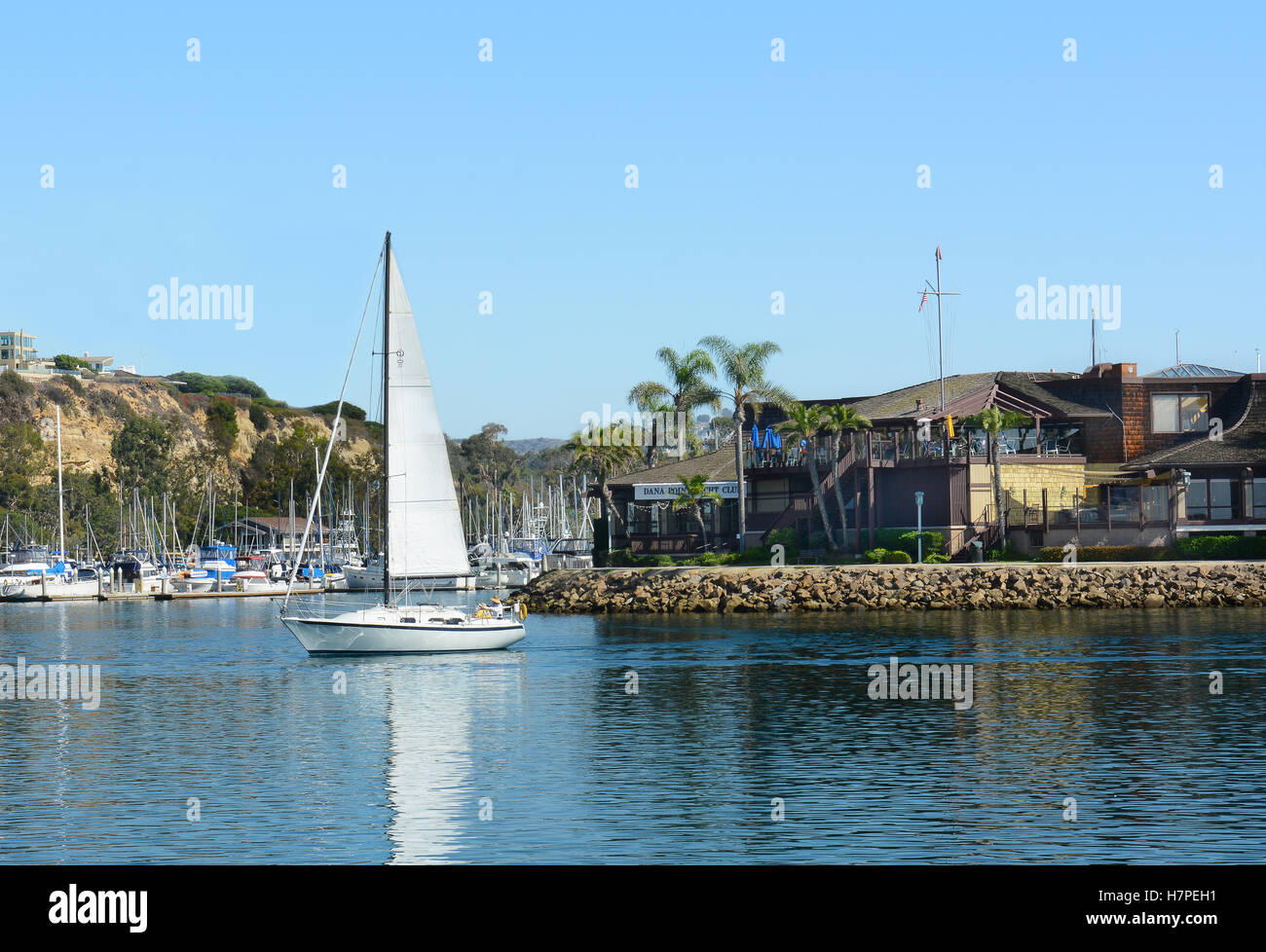 Dana Point Yacht Club avec la voile en passant en face. Banque D'Images