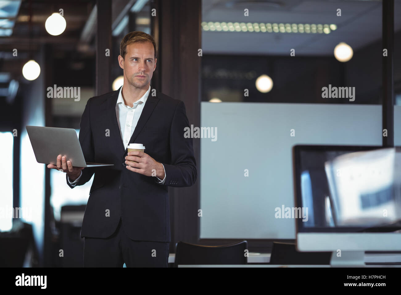 Businessman standing avec un ordinateur portable et Coffee cup Banque D'Images