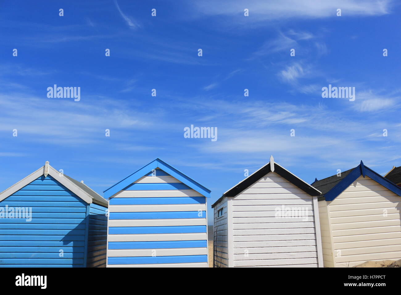 Une rangée de cabanes de plage contre un ciel bleu à plage de Southwold. Les nuages blancs pâles streak à travers le ciel. Banque D'Images