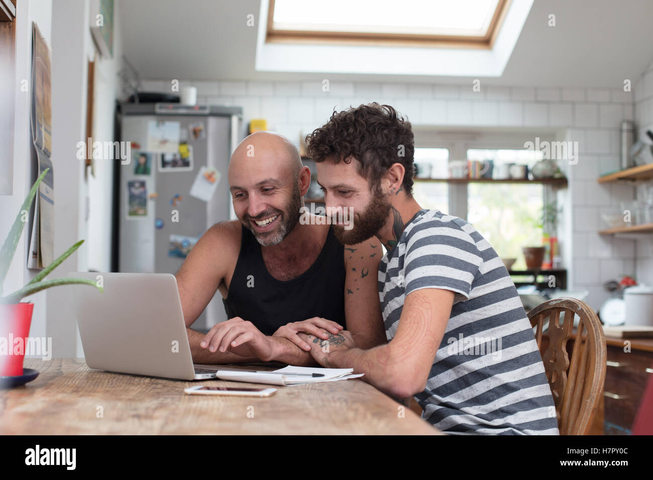 Gay couple using laptop in kitchen Banque D'Images