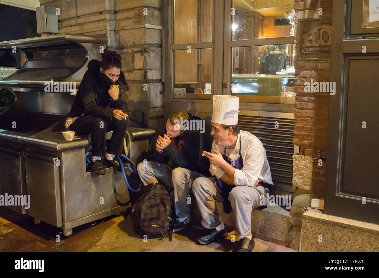 Un chef portant une toque et amis fumeurs à l'extérieur de la Brasserie Flo la nuit, Toulouse, Haute-Garonne, Occitanie, France Banque D'Images