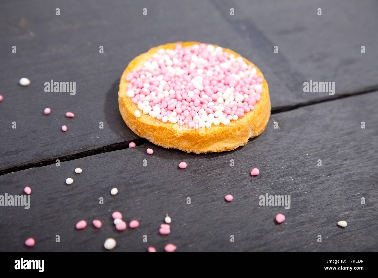 Célébration de naissance traditionnel néerlandais biscuit rose avec muisjes sur fond de bois Banque D'Images