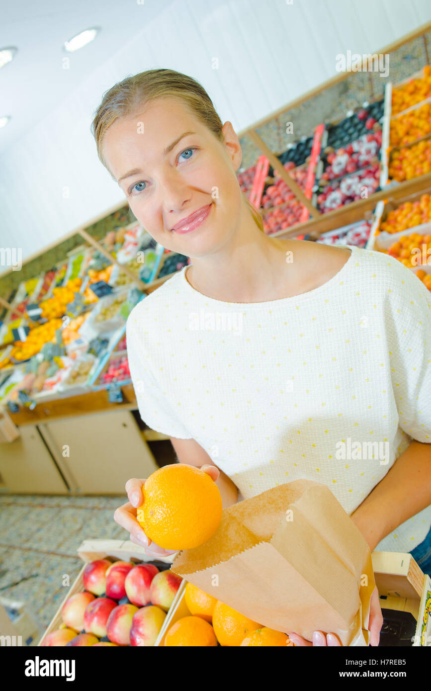 Jeune femme en mettant une orange dans un sac en papier Banque D'Images