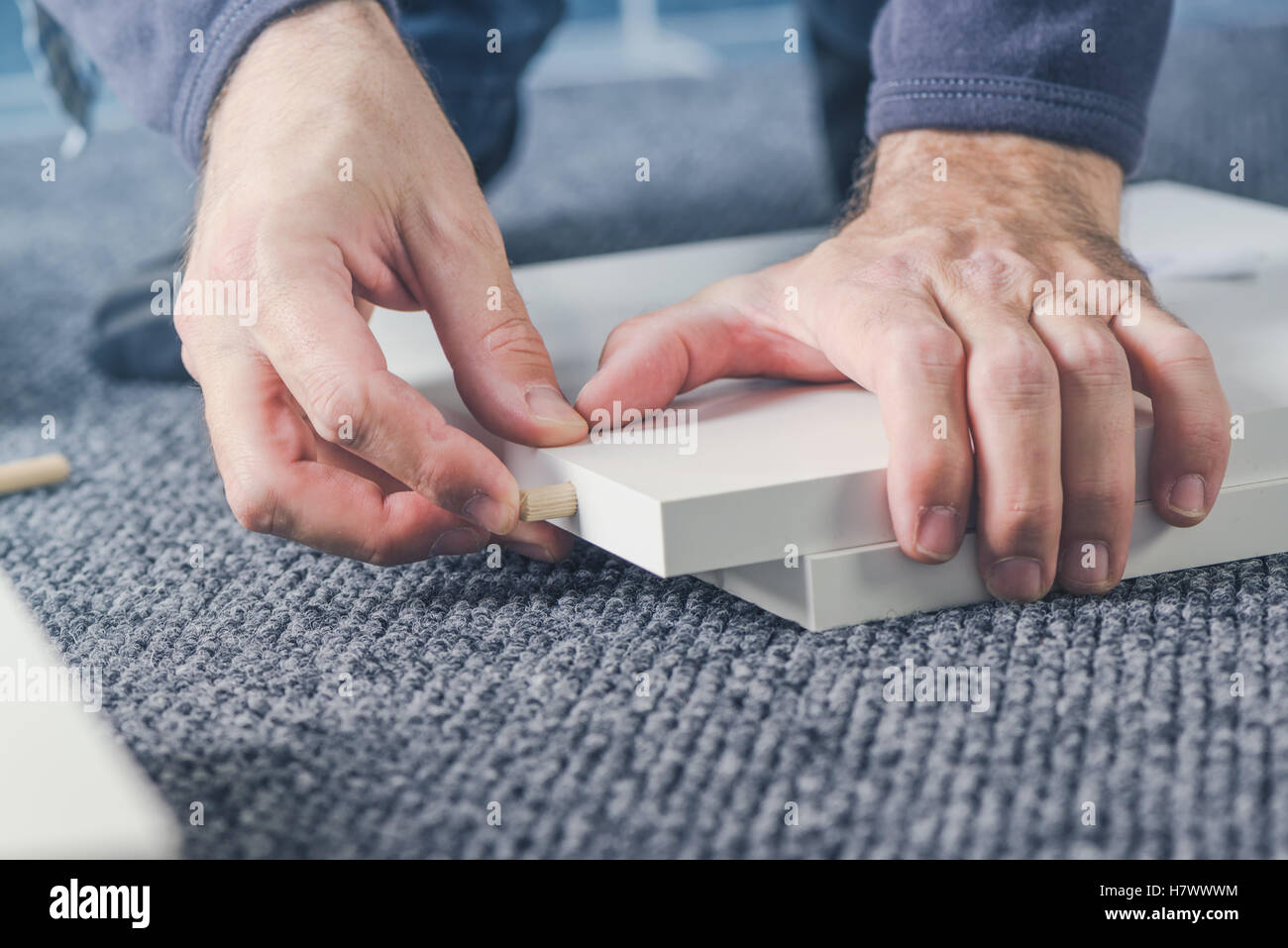Homme montage de meubles à domicile, homme part avec chevilles en bois et contreplaqué Banque D'Images