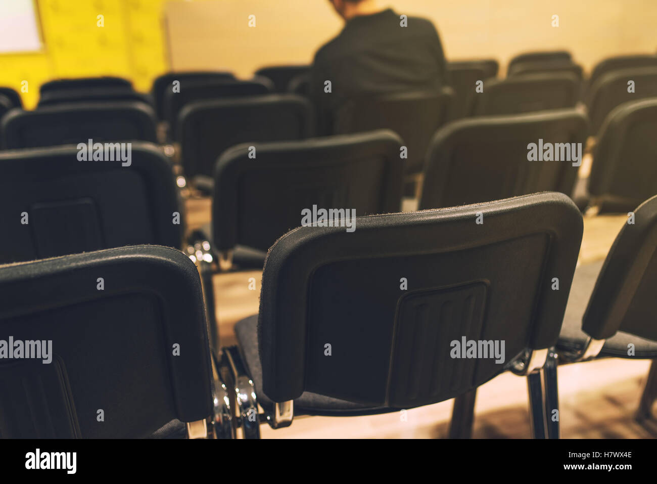 Méconnaissable journaliste en salle de conférence de presse, assis seul au milieu des chaises vides, selective focus Banque D'Images