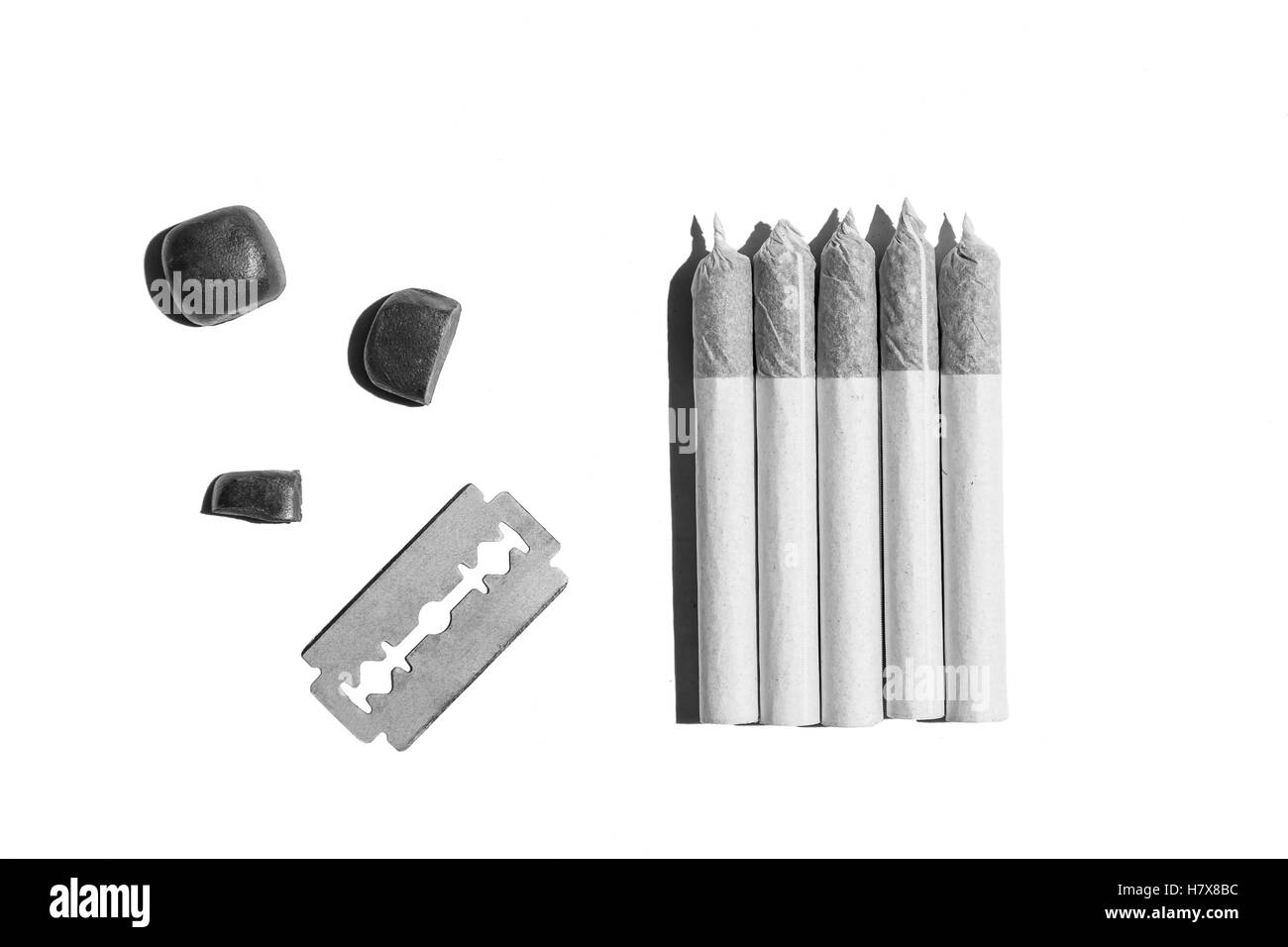 Les cigarettes roulées de chanvre.Cinq cigarettes roulées de cannabis, blade et les pierres sont isolés sur le fond blanc. Banque D'Images