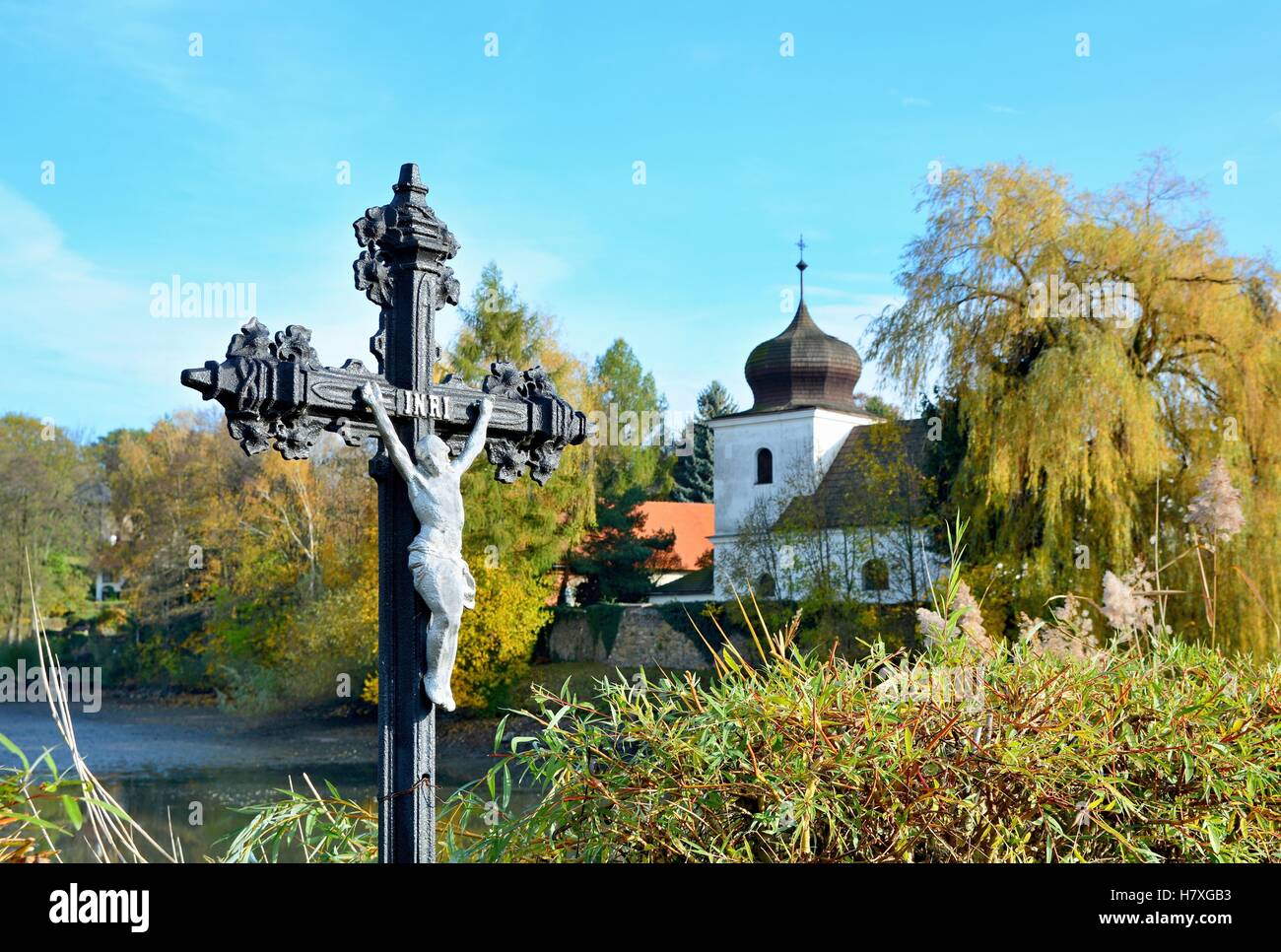 Jésus sur la croix à l'extérieur dans la nature avec l'église en arrière-plan. Banque D'Images