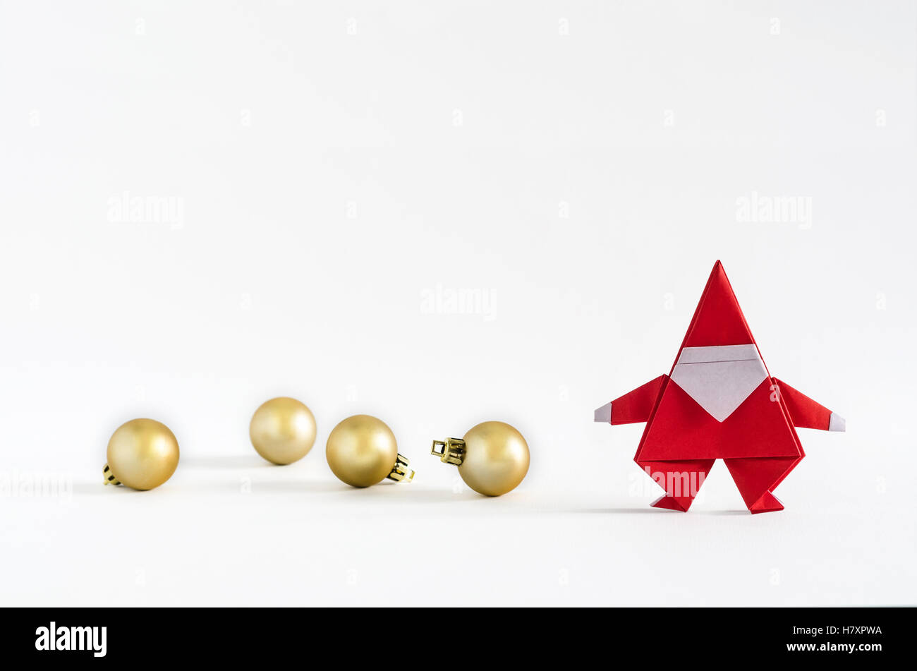 Père Noël en papier et boule d'or sur fond blanc. Origami Papier. Banque D'Images
