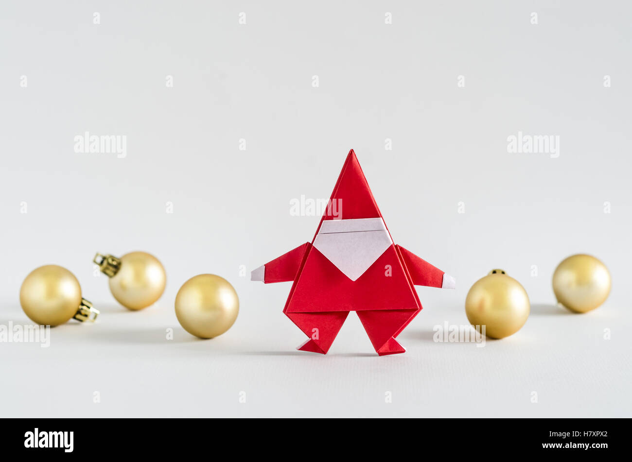 Père Noël en papier et boule d'or sur fond blanc. Origami Papier. Banque D'Images