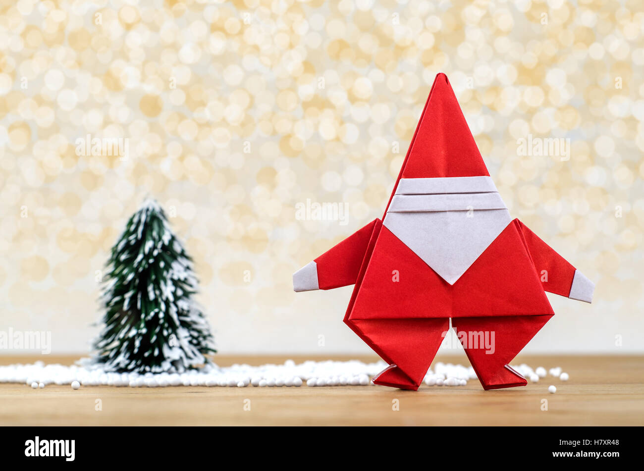 Père Noël en papier et l'arbre de Noël avec des lumières de l'hiver la neige fond. Origami Papier. Banque D'Images