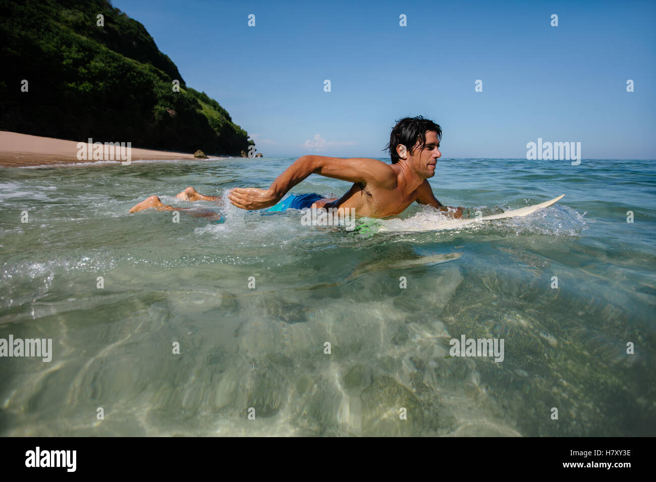 Vue latérale de l'eau coup de jeune homme surf dans l'océan. Homme surfer dans l'eau de mer avec planche de surf. Banque D'Images