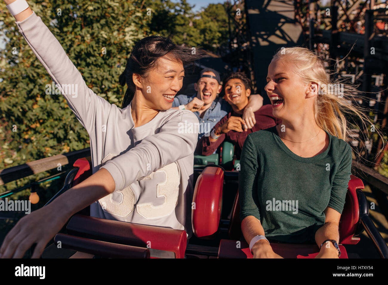 Shot of young friends enjoying et acclamant tour de caboteur de rouleau. Les jeunes s'amuser sur rollercoaster à amusement park. Banque D'Images