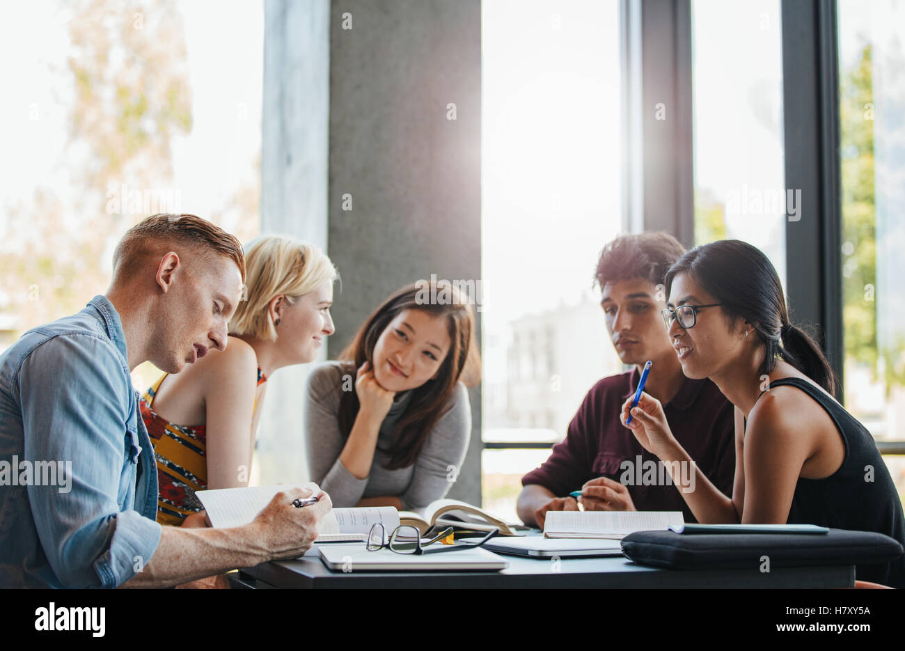 Groupe d'étudiants de l'école faire cession de bibliothèque. Les jeunes multiethniques de la lecture d'ouvrages de référence pour l'étude. Banque D'Images