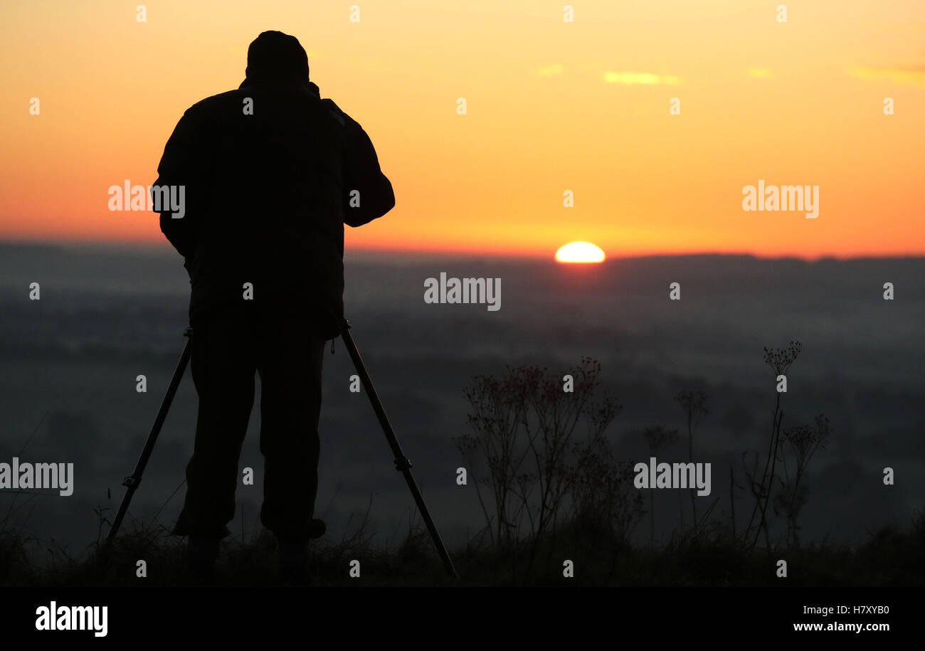 Un photographe capte le soleil qu'il s'élève au-dessus de la vallée de Pewsey près de Marlborough dans le Wiltshire, à mesure que l'hiver s'est mis à balayer au début le mardi de avec beaucoup de neige jusqu'à 15cm (6pouces) de profondeur menacé d'introduire une perturbation de voyage. Banque D'Images