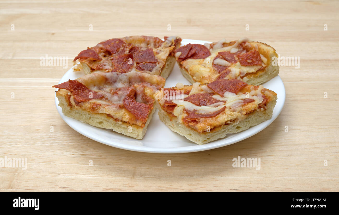 Micro-ondes plusieurs tranches de la pizza au pepperoni de format  individuel isolé sur une plaque blanche au sommet d'une table en bois Photo  Stock - Alamy