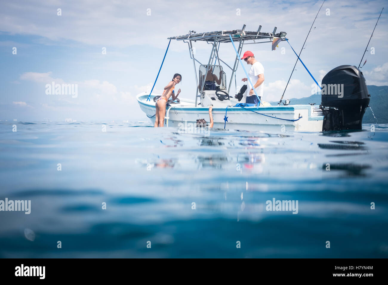 Les gens s'amusant à la natation et la plongée avec tuba à côté de petit bateau de pêche Banque D'Images