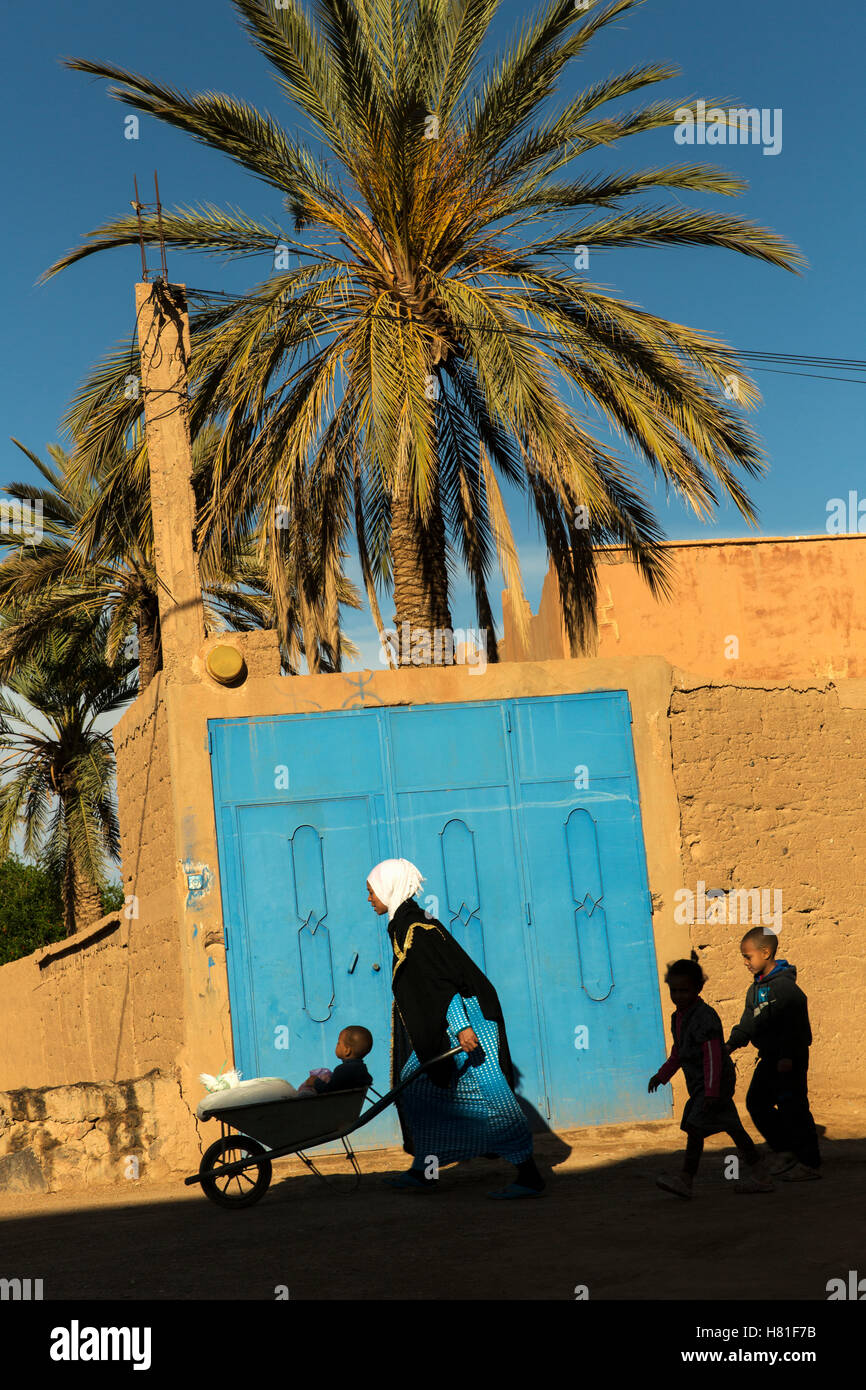 Maroc, Tinejdad, Vallée du Todra, Ksar El Khorbat, femme poussant la brouette avec des enfants qui suivent, un Ksar est un village entouré de murs, Banque D'Images