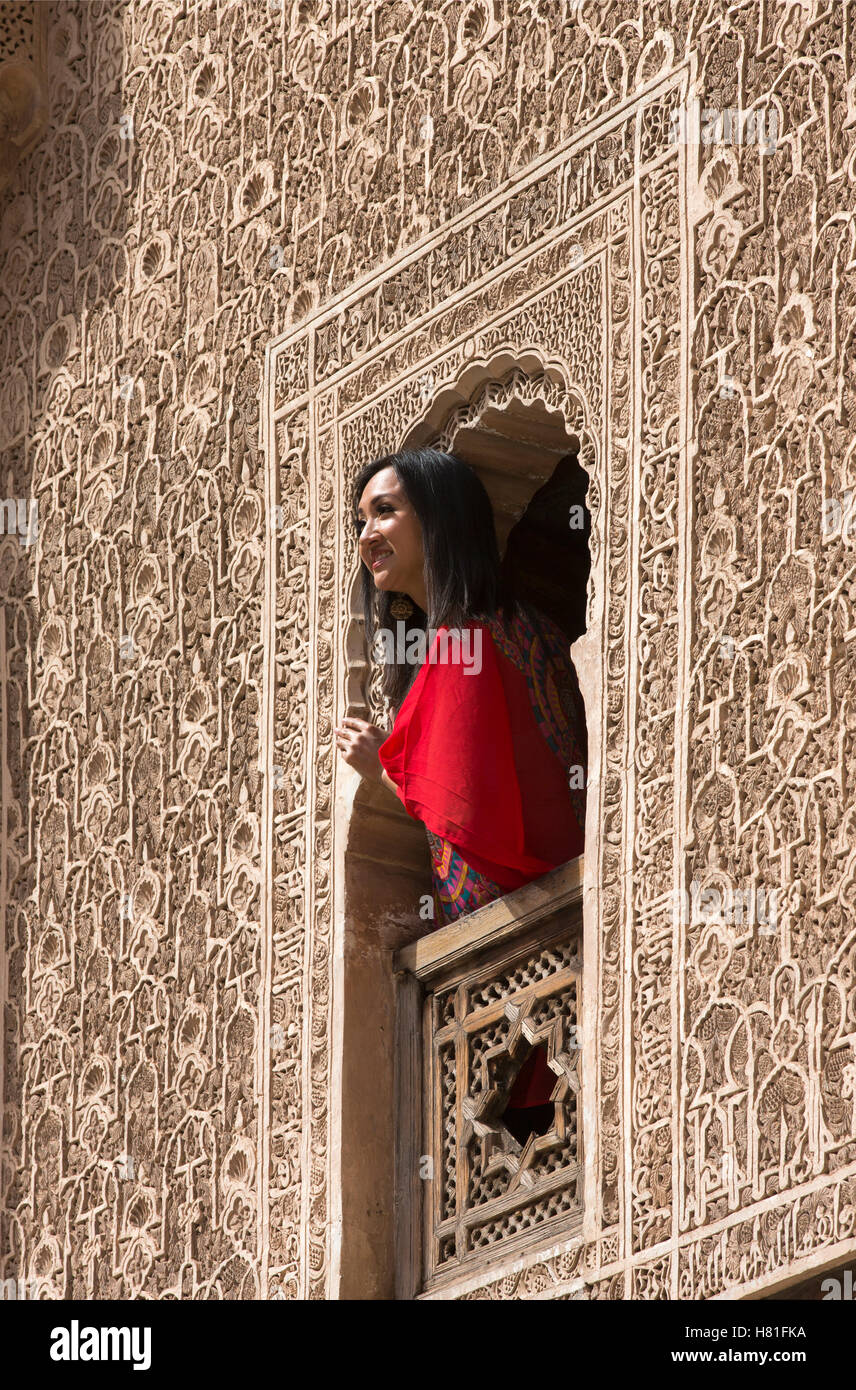 Maroc,Marrakech,Medersa Ben Youssef,construit 1564, woman peering à partir d'une fenêtre décorée Banque D'Images