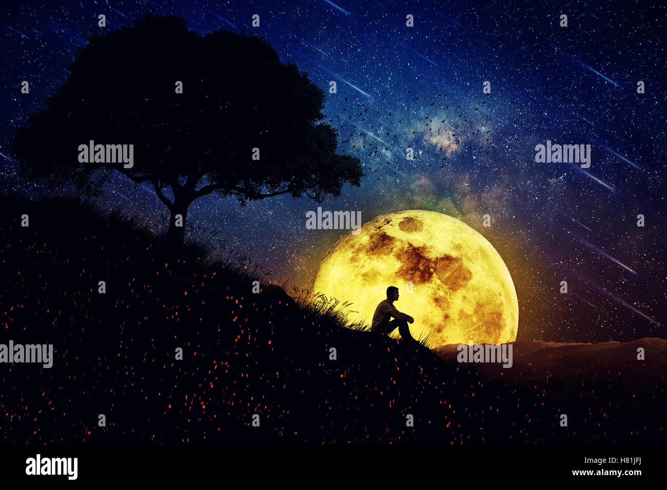 Garçon assis seul sur une colline dans le centre de la nature, au cours d'une nuit de pleine lune. Debout à l'écart de la foule, en attente d'e Banque D'Images