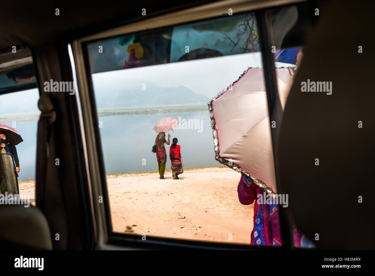 Femmes marchant sur le côté du lac Phewa ; vues à travers la fenêtre de voiture à Kaski, Gandaki, Népal. Le lac Phewa est l'un des lacs qui se rétrécissent en Asie du Sud. Banque D'Images