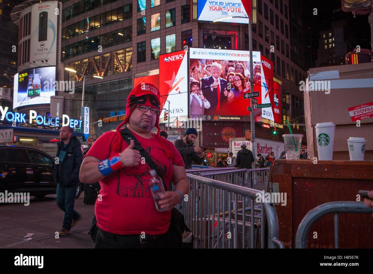 New York, NY, USA - 9 novembre 2016. 3:13 AM : un atout partisan (premier plan) gestes en regardant le photographe à Times Square et bien que Trump est montré sur un écran derrière lui faisant le même geste. Photo : Alessandro Vecchi dpa Banque D'Images