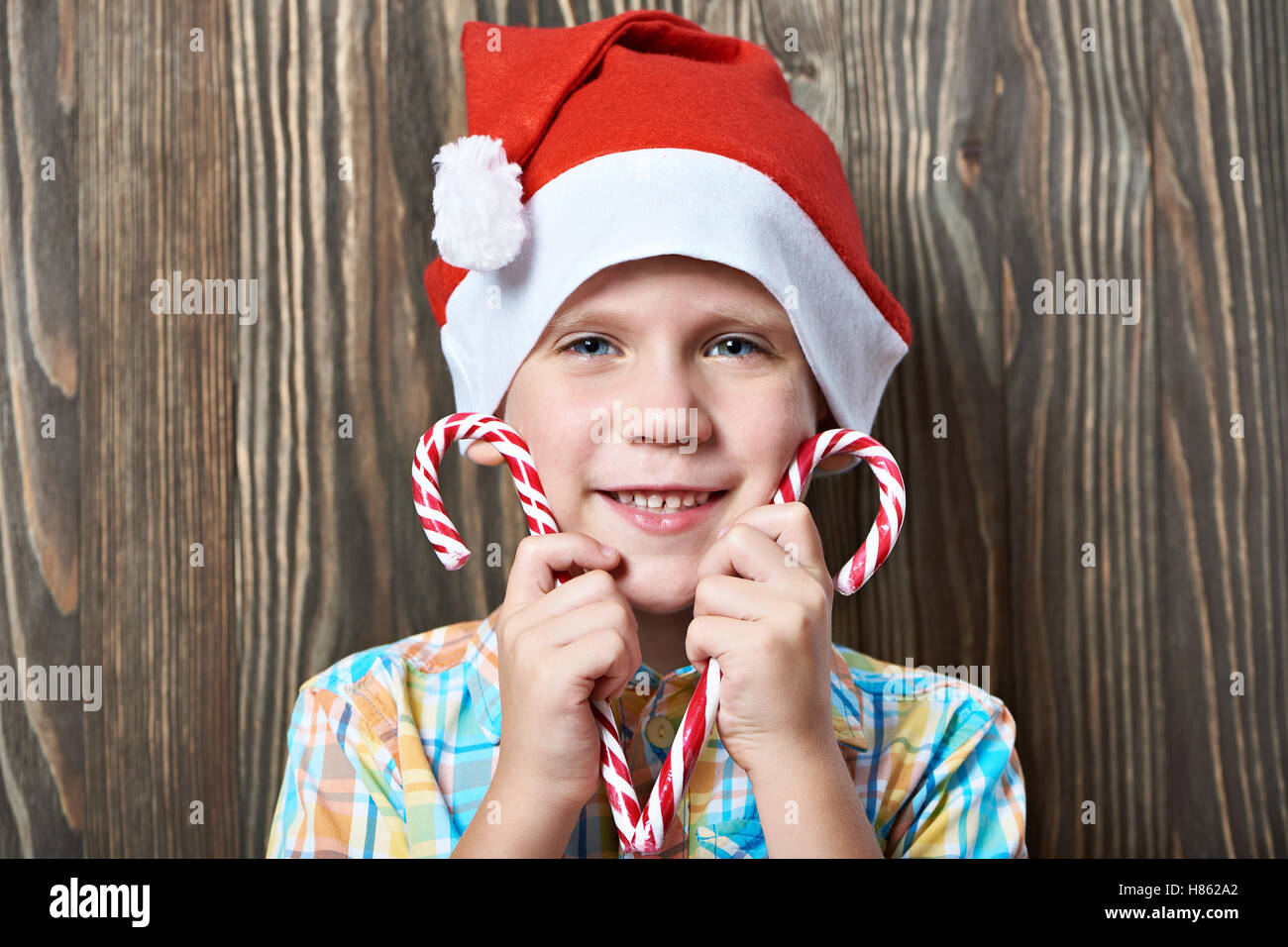 Petit garçon dans une nouvelle année, le bonnet rouge avec deux cannes de bonbons de Noël Banque D'Images
