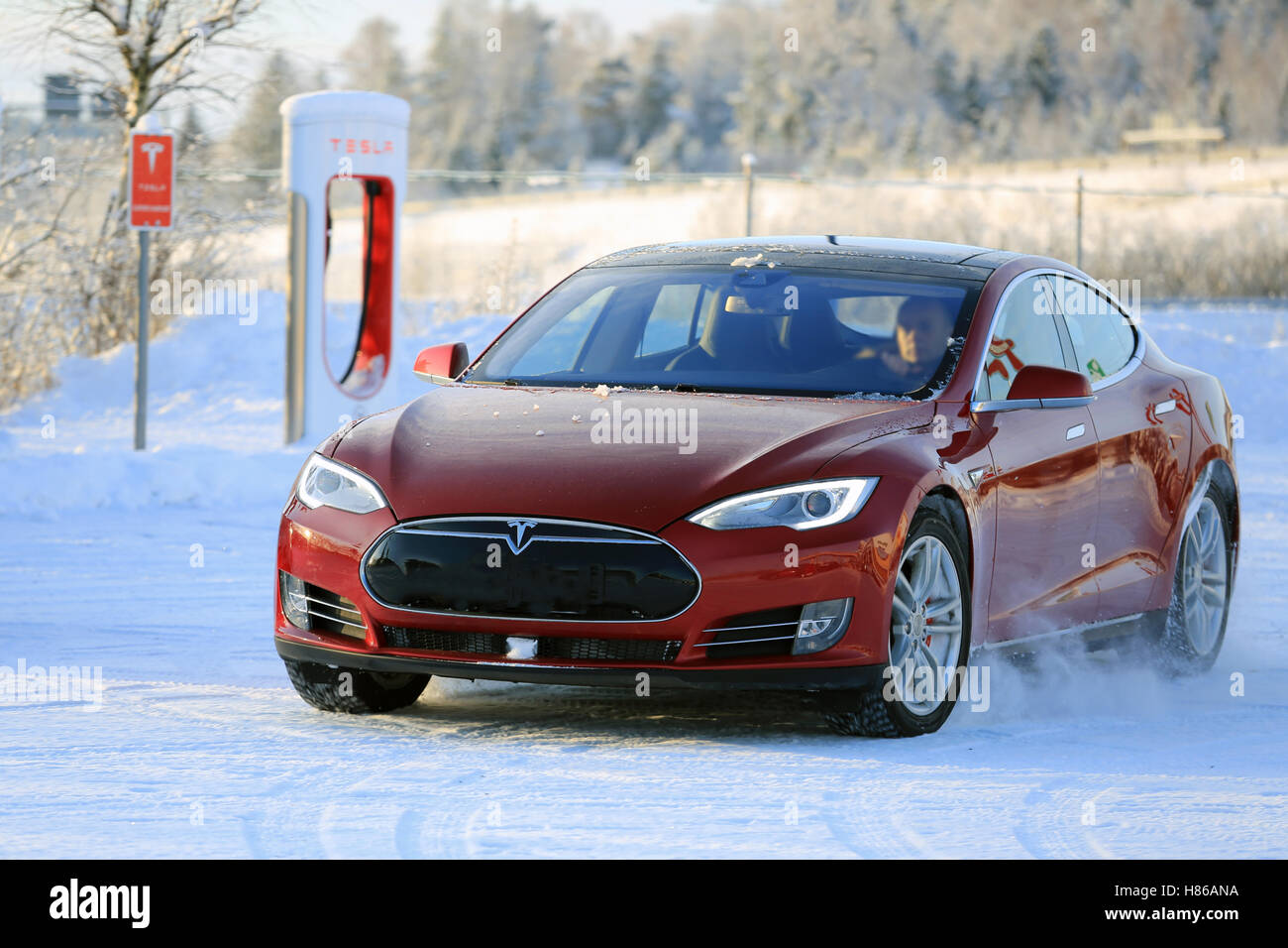 PAIMIO, FINLANDE - le 17 janvier 2016 : les lecteurs de l'homme sans nom Tesla Model S rouge à l'harfang Supercharger Gare Paimio. Banque D'Images