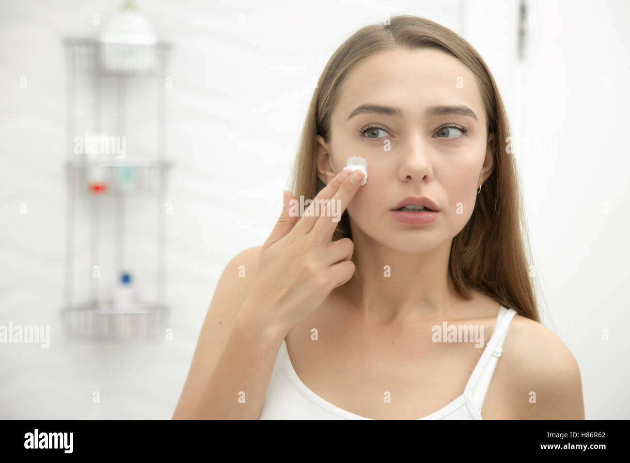 Young Beautiful woman applying cream à face dans la salle de bains Banque D'Images