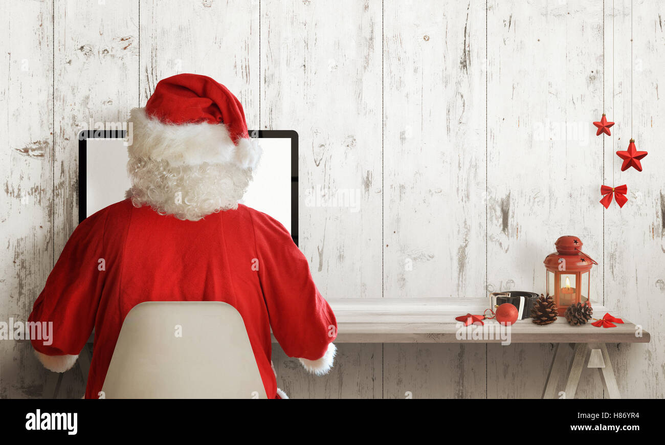 Père Noël shopping sur ordinateur. Vente de Noël le temps. Espace libre pour le texte. Décorations de Noël à côté. Banque D'Images