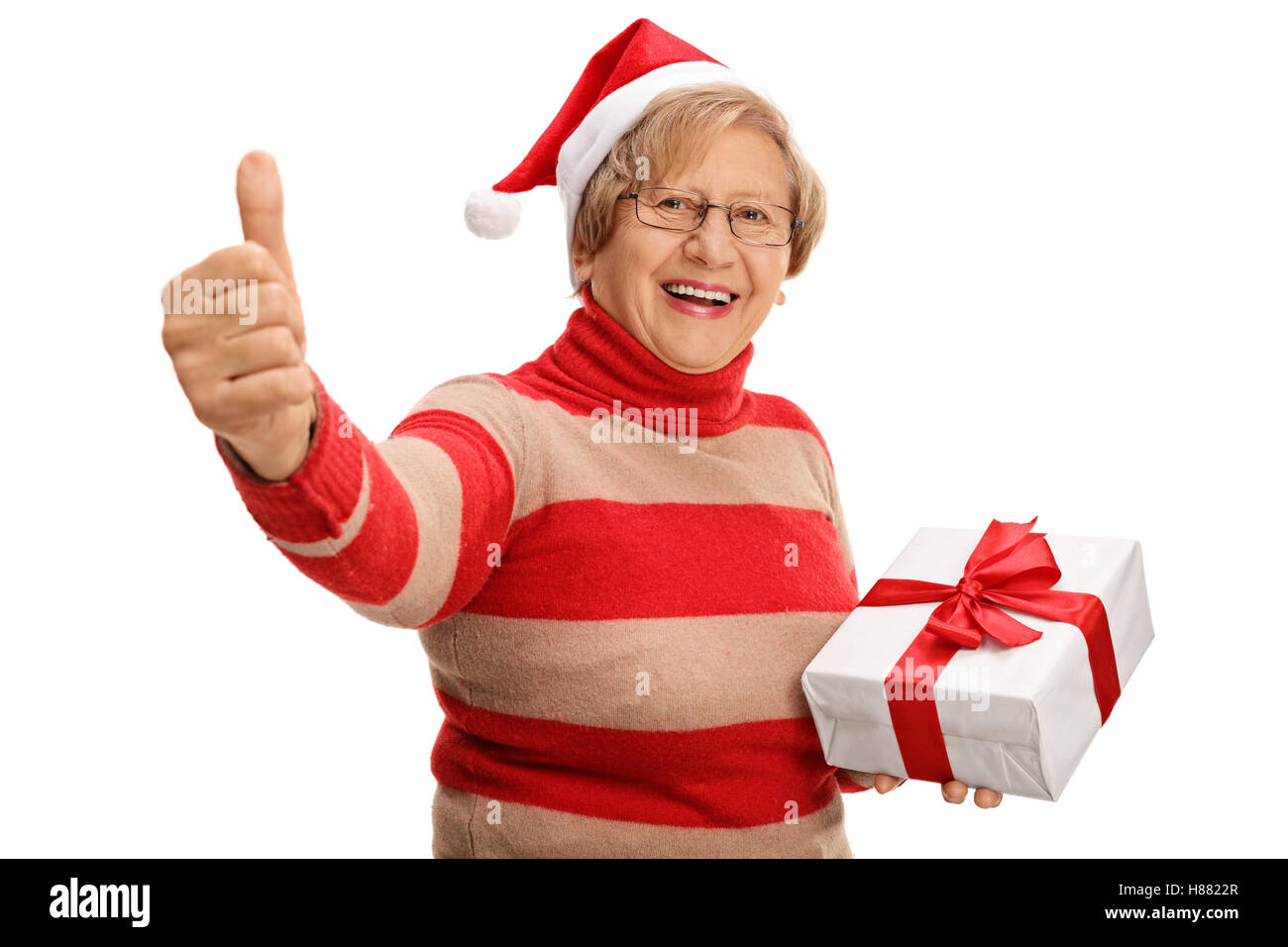 Cheerful senior tenant un cadeau de noël et donner un pouce vers le haut isolé sur fond blanc Banque D'Images