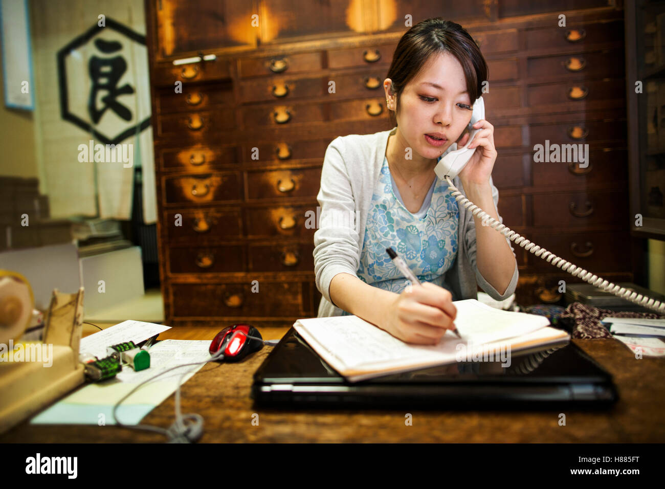 Bonbons appelé wagashi. Une femme prendre une commande par téléphone et par écrit avec un stylo. Banque D'Images