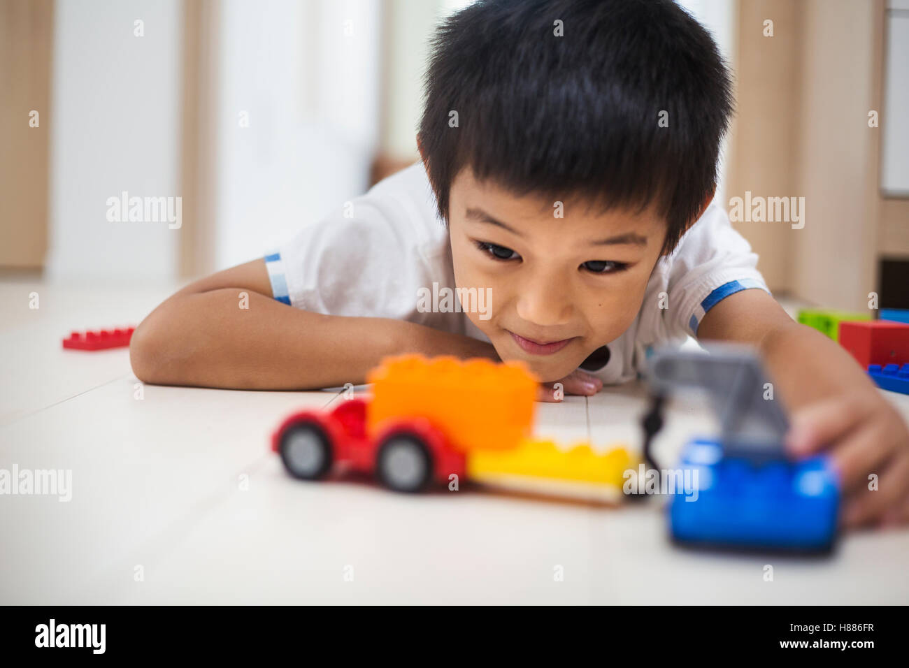 Maison de famille. Un garçon jouant avec des voitures sur le plancher. Banque D'Images
