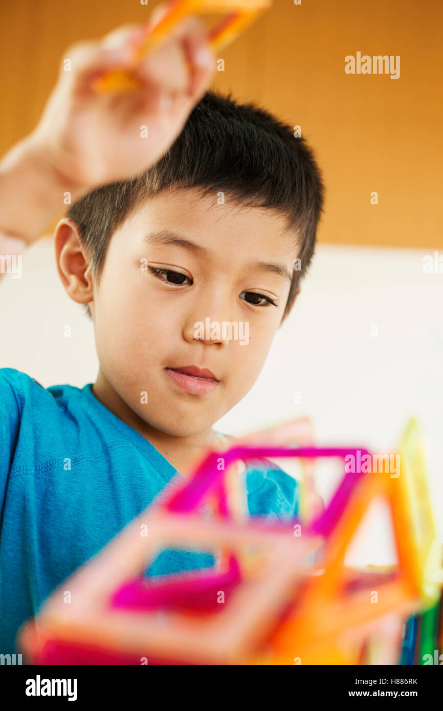 Un garçon jouant avec formes géométriques colorées dans une salle de classe la construction d'un ouvrage de formes tri Banque D'Images